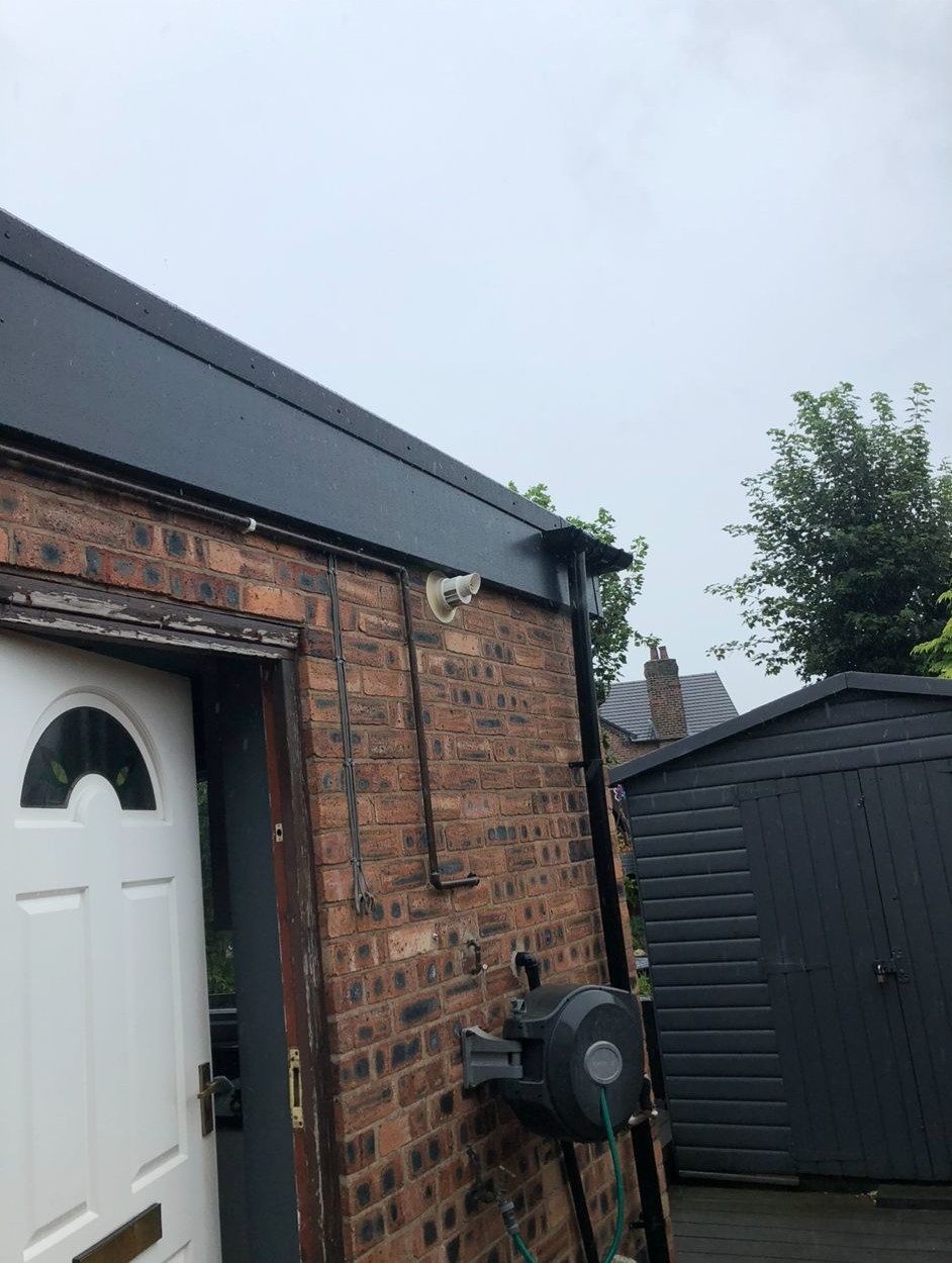 New black fascia board and guttering fitted to a brick house extension