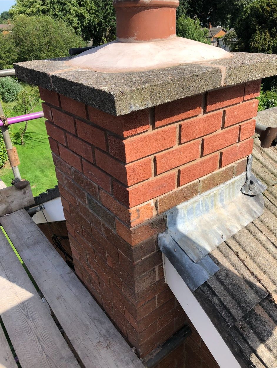 Brick chimney on a tiled roof with new lead flashing dressed around its base